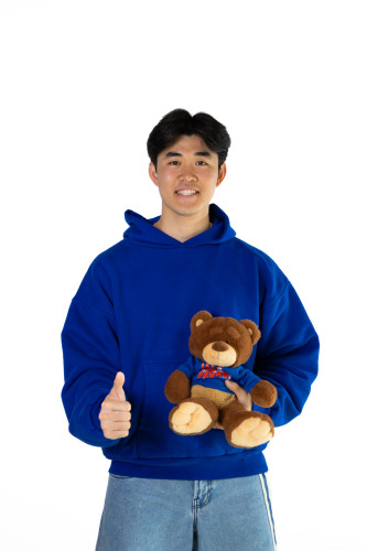 Chris smiling while holding a Bruno bear stuffed animal with a thumbs up