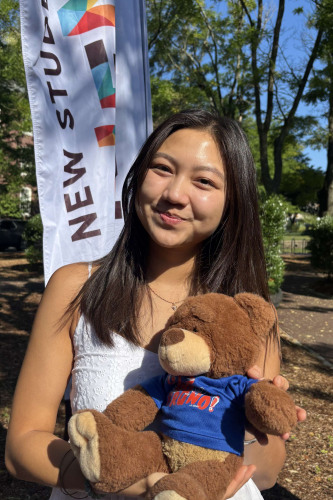 Amy smiling outside in front of a New Student Orientation flag