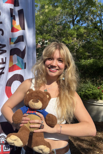 Camille smiling outside in front of a New Student Orientation flag
