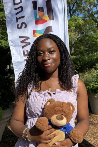 Faith smiling outside in front of a New Student Orientation flag