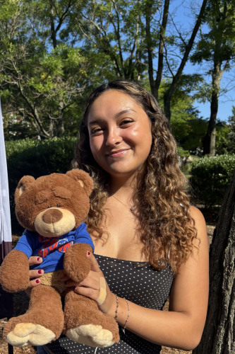 Ivy smiling outside in front of a New Student Orientation flag