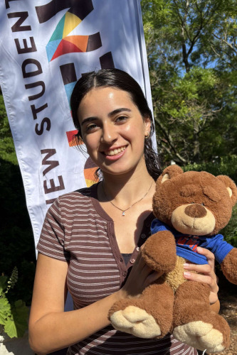 Kiana smiling outside in front of a New Student Orientation flag