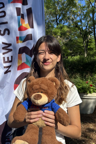 Kiera smiling outside in front of a New Student Orientation flag