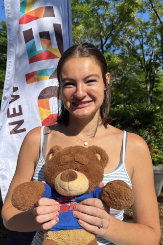 Lainey smiling outside in front of a New Student Orientation flag