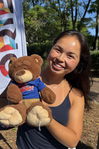 Mai smiling outside in front of a New Student Orientation flag
