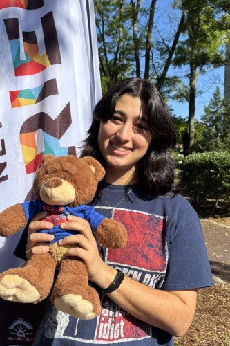 Mayan smiling outside in front of a New Student Orientation flag