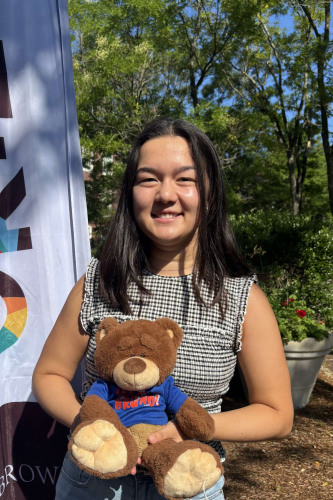 Monica smiling outside in front of a New Student Orientation flag