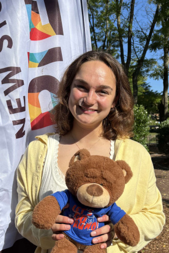 Reese smiling outside in front of a New Student Orientation flag