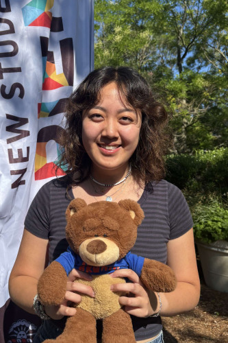 Vanessa smiling outside in front of a New Student Orientation flag