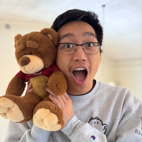 Avery posing with a Bruno bear stuffed animal while making a surprised face