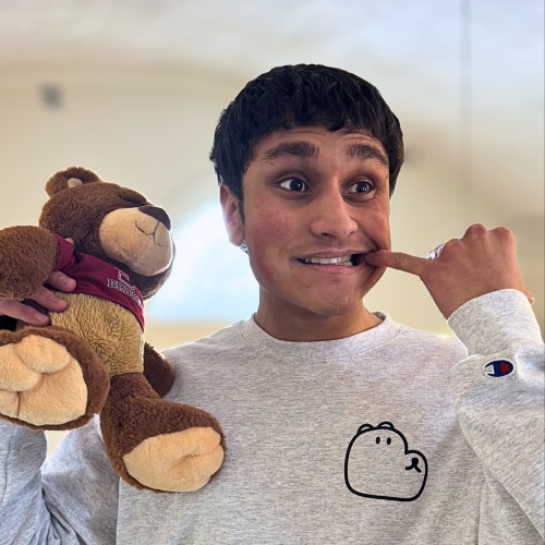 Akshat posing with a Bruno bear stuffed animal with his pinky on his cheek