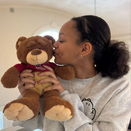 Abigail holding teddie bear bruno and giving him a kiss on the cheek