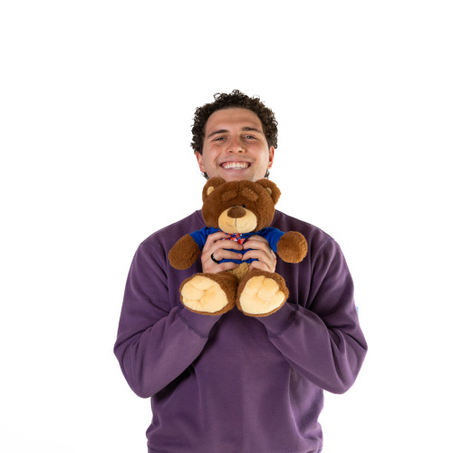 Luca  smiling while holding out a Bruno bear stuffed animal