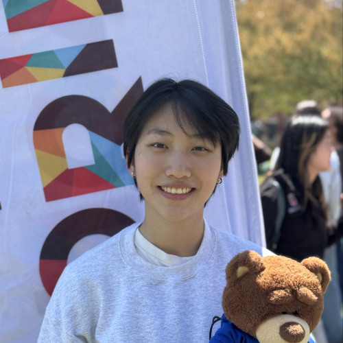 Alec outdoors smiling with a Bruno stuffy