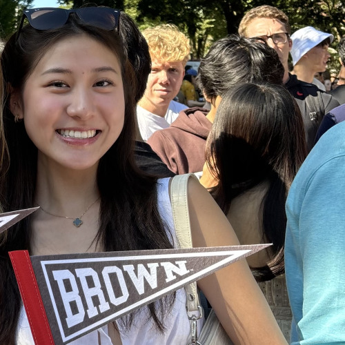 Student standing in group of other students holding a Brown University flag