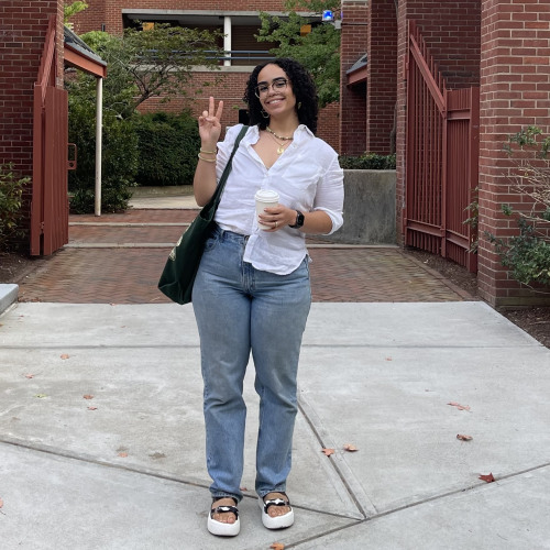 Student posing outside and holding a coffee
