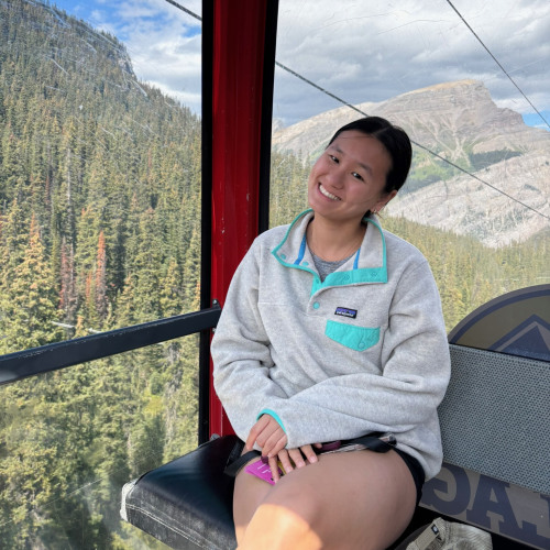 Student smiling on ski life in air on top of forest