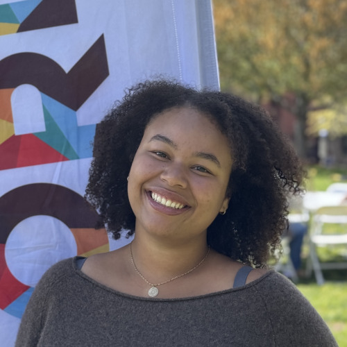 Mares smiling outside in front of an orientation flag