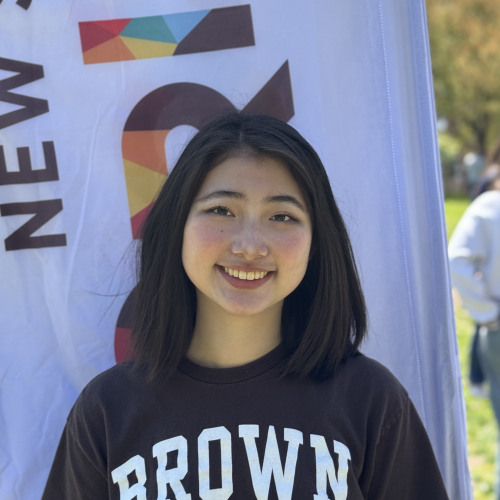 Michelle smiling outside in front of an orientation flag