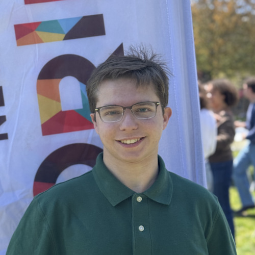 Neil smiling outside in front of an orientation flag