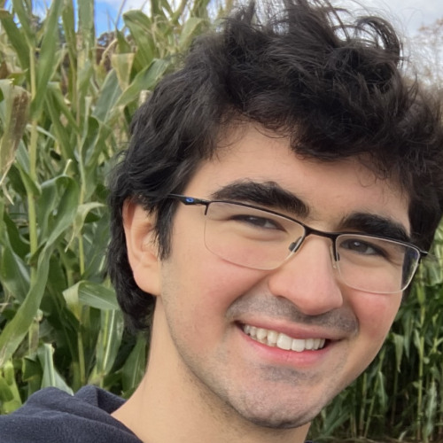 Student smiling in front of corn field