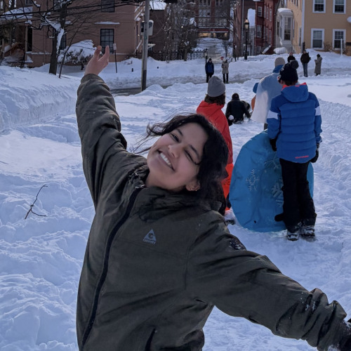 Student posing in snow with city in background