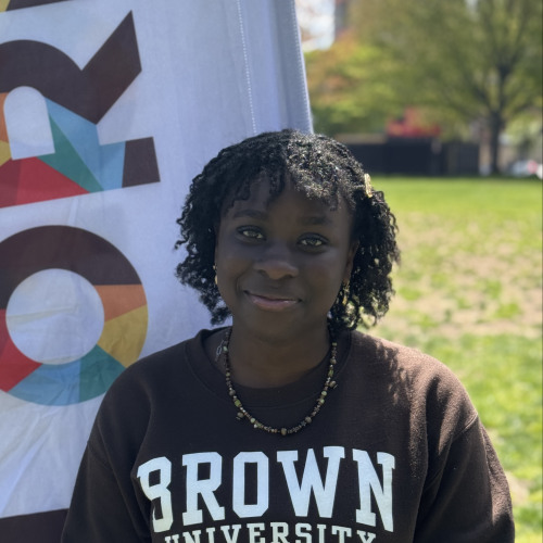 Faith smiling outside in front of a New Student Orientation flag