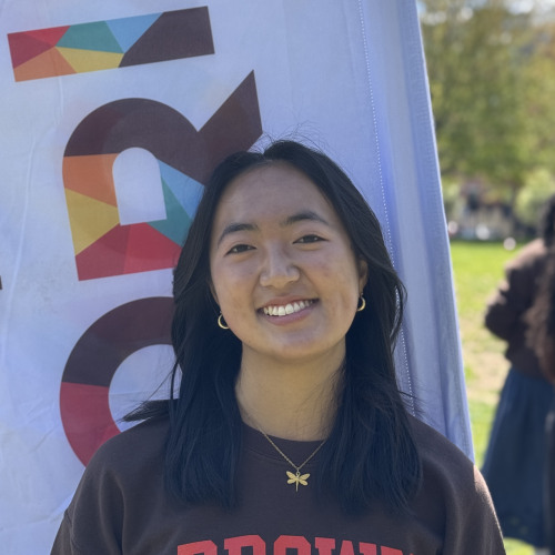 Michelle smiling outside in front of an orientation flag