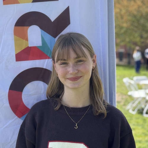 Elle smiling outside in front of an orientation flag