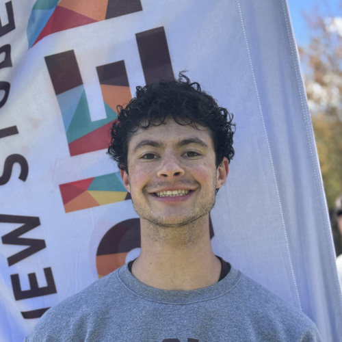 Jared smiling outside in front of an orientation flag