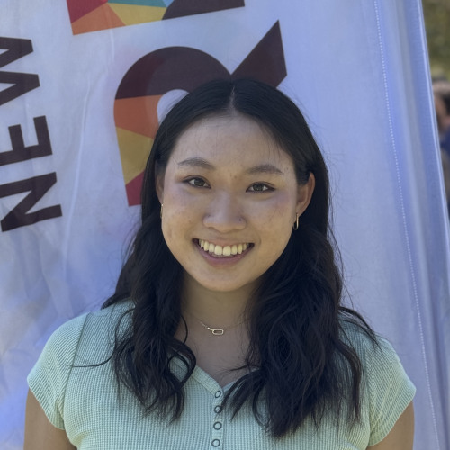 Ashley smiling outside in front of an orientation flag