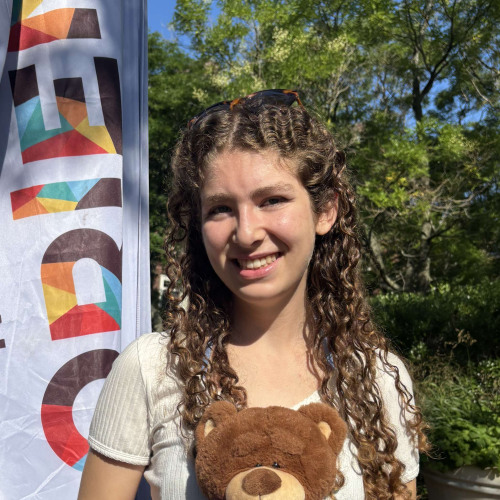 Becca smiling outside in front of a New Student Orientation flag