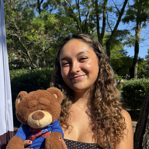 Ivy smiling outside in front of a New Student Orientation flag