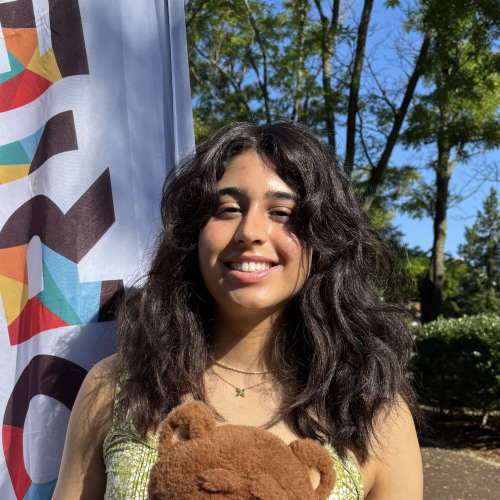 Lauren smiling outside in front of a New Student Orientation flag